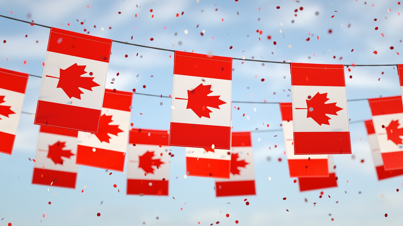 Three Rows of Garlands of Canadian Flags Against a Slightly Cloudy Blue Sky with Red and White Confetti Falling in the Air